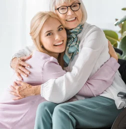 smiling-woman-hugs-senior-woman-in-wheelchair